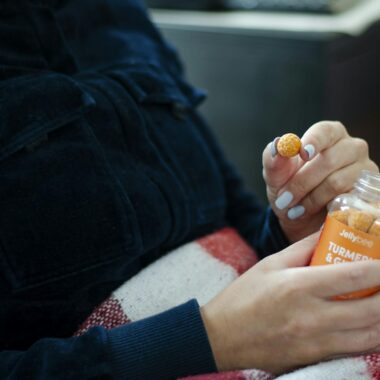 A person holding a bottle of turmeric gummies, showcasing their use as dietary supplements.