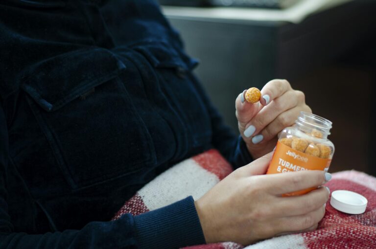A person holding a bottle of turmeric gummies, showcasing their use as dietary supplements.