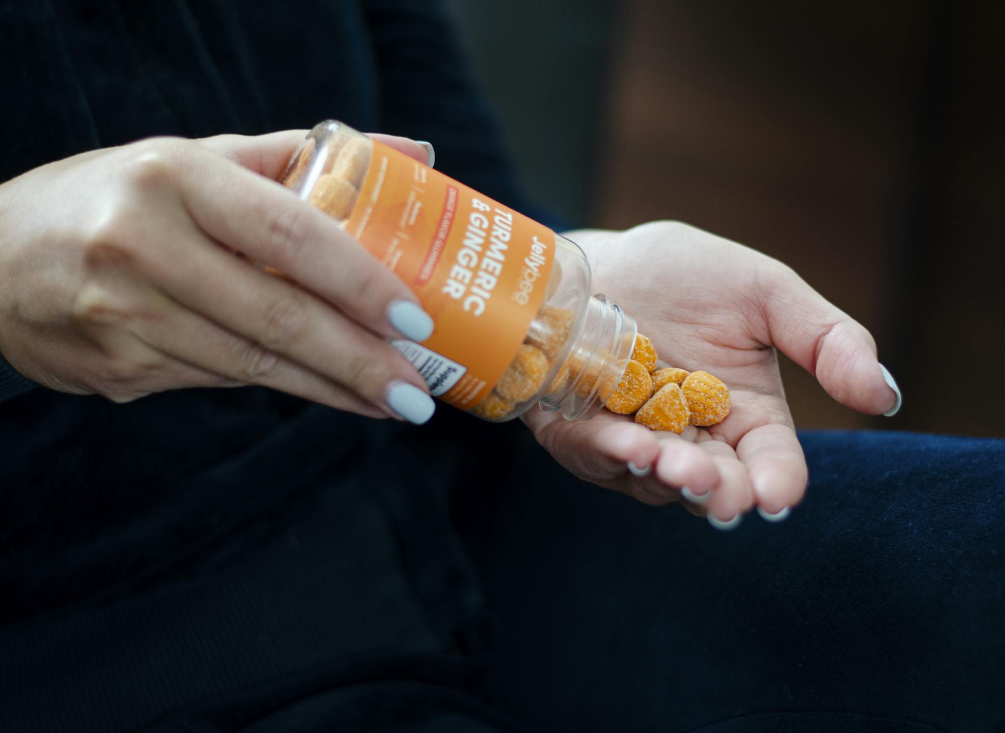 Close-up of a woman holding turmeric ginger gummies in hand, promoting a health supplement.