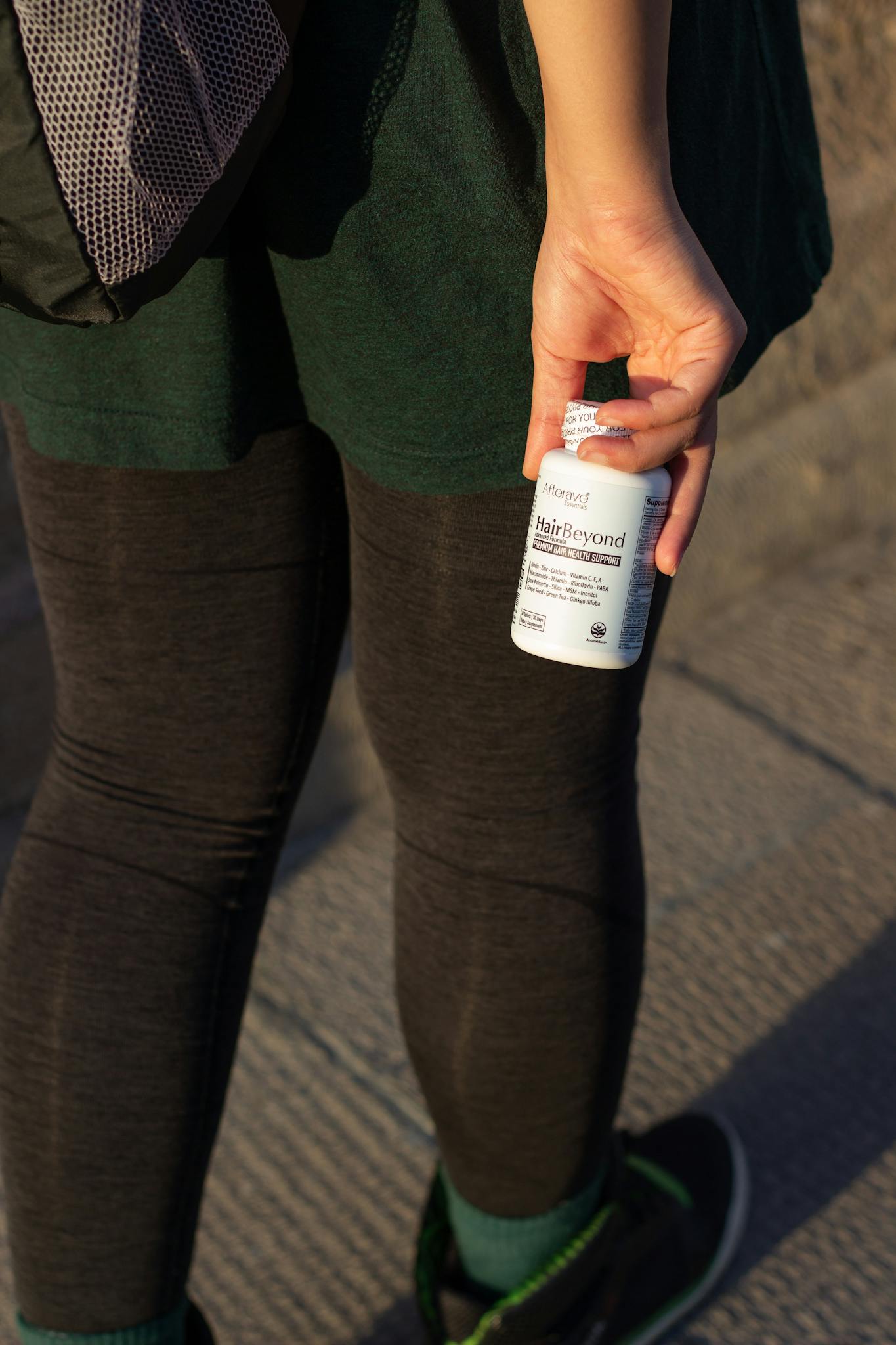Individual holding vitamin bottle in sunny Los Angeles street. Perfect for health and lifestyle themes.